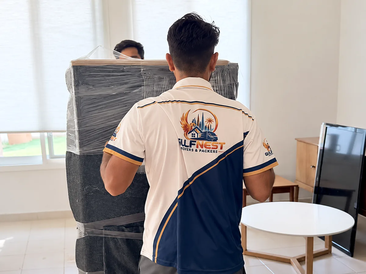 GulfNest uniformed mover handling protected furniture during a residential move