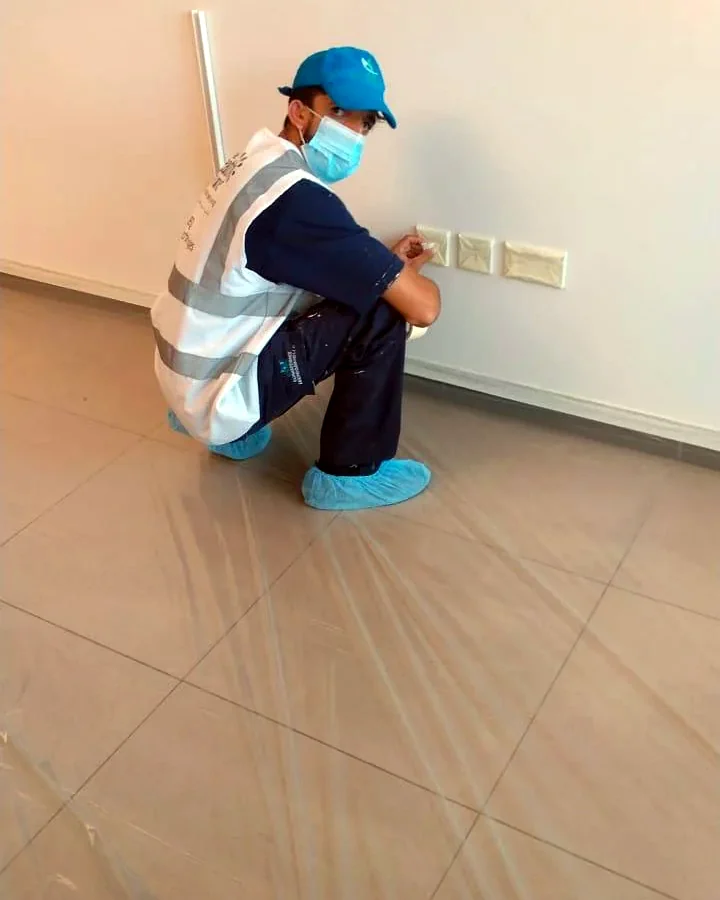 GulfNest painter protecting switches and floor before apartment painting in Dubai